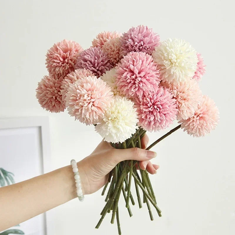 Mano de mujer sujetando un ramo de hortensias artificiales de colores rosas y blancos.