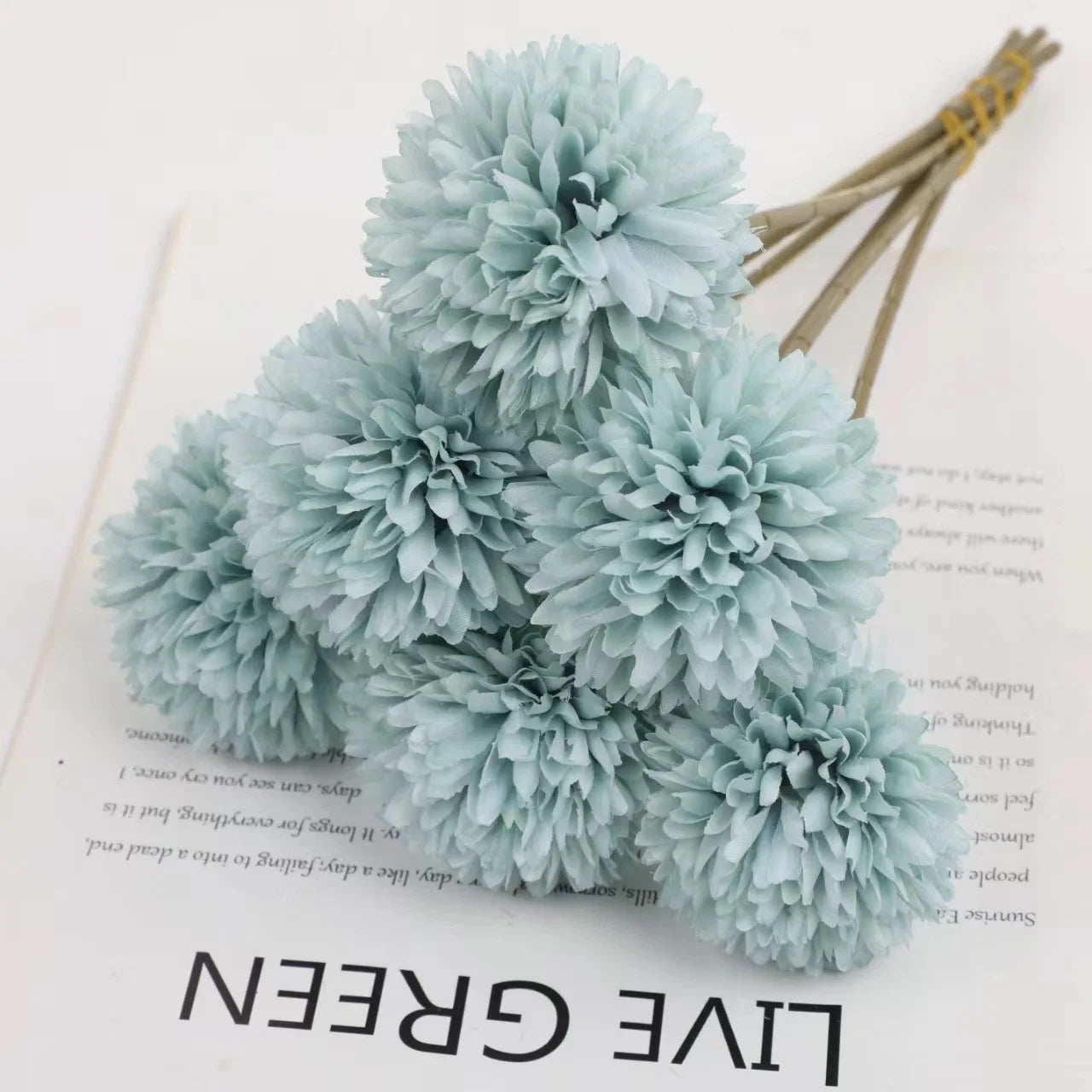 ramo de hortensias azules sobre una hoja de papel con letras negras que pone live green