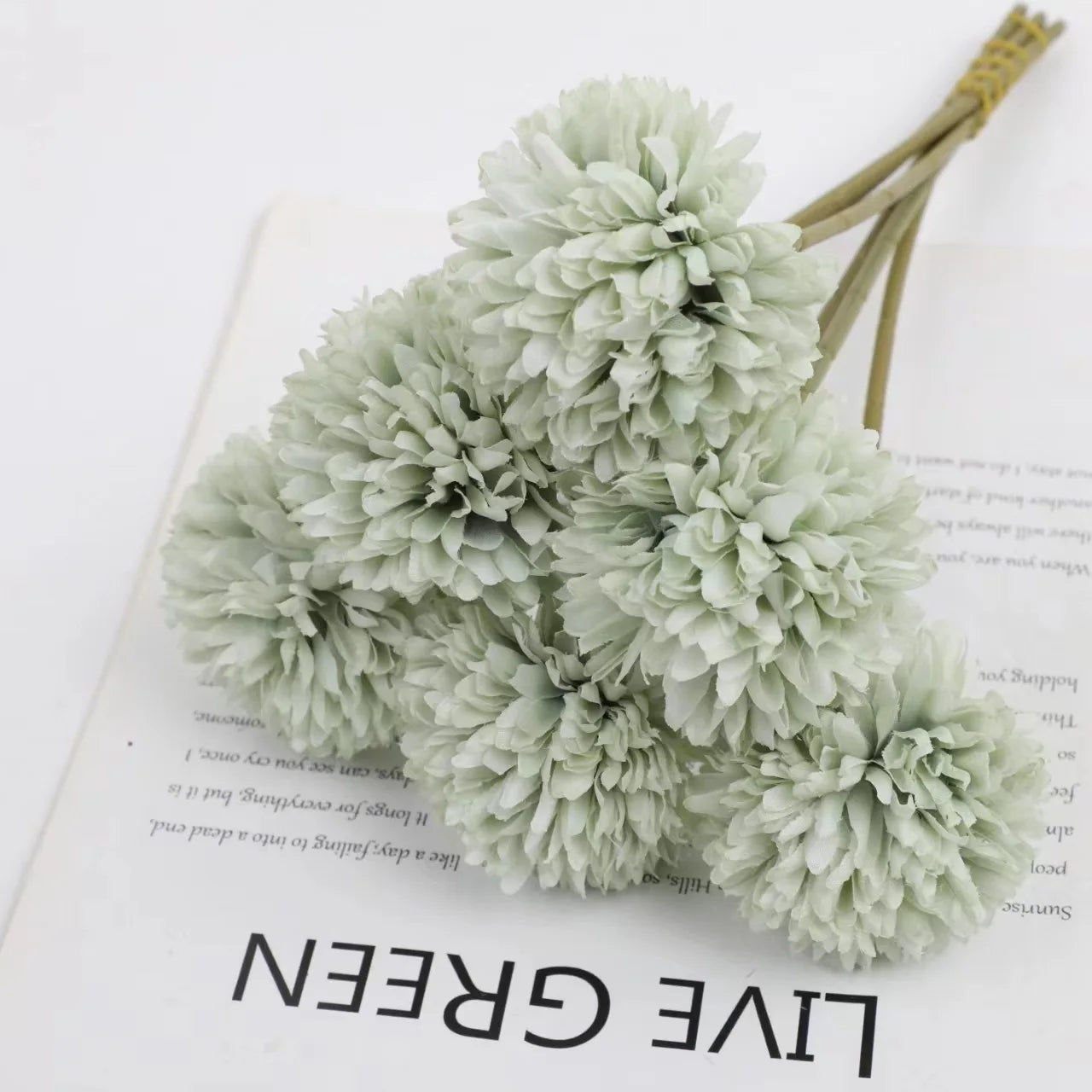 ramo de hortensias grises sobre una hoja de papel con letras negras que pone live green