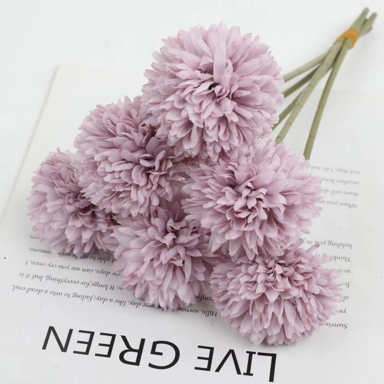 ramo de hortensias violetas sobre una hoja de papel con letras negras que pone live green